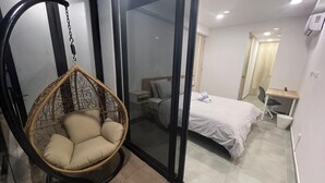 Une chambre à coucher avec un lit, un fauteuil suspendu, un bureau et une fenêtre.