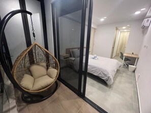 A bedroom with a bed, a hanging chair, a desk, and a window. - Samaia Loft (Santa Marta)