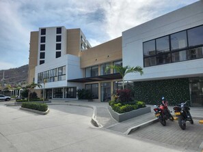 A modern building with large windows, a parking area, and two motorcycles parked outside. - Samaia Loft (Santa Marta)