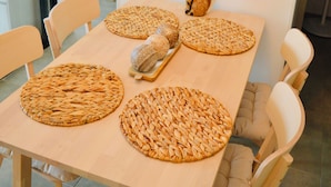 Une table à manger agrémentée de sets de table en fibres tressées, d’un miroir décoratif et d’une figurine de renard.