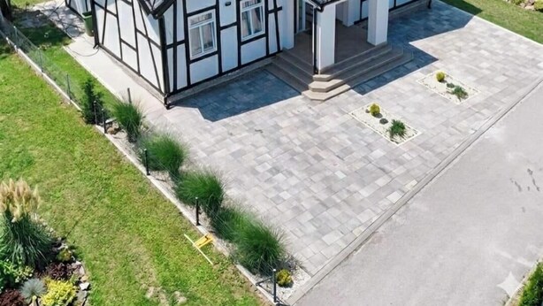 Uma casa grande e moderna com design simétrico, apresentando uma entrada central, várias janelas e um gramado bem cuidado.