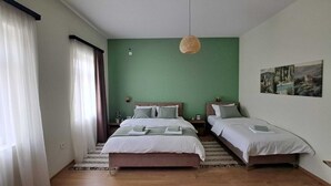 Quarto com duas camas, um candeeiro pendente e um quadro na parede.