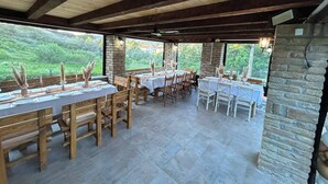 Restaurante com mesas ao ar livre, paredes de pedra e vista para o verde.