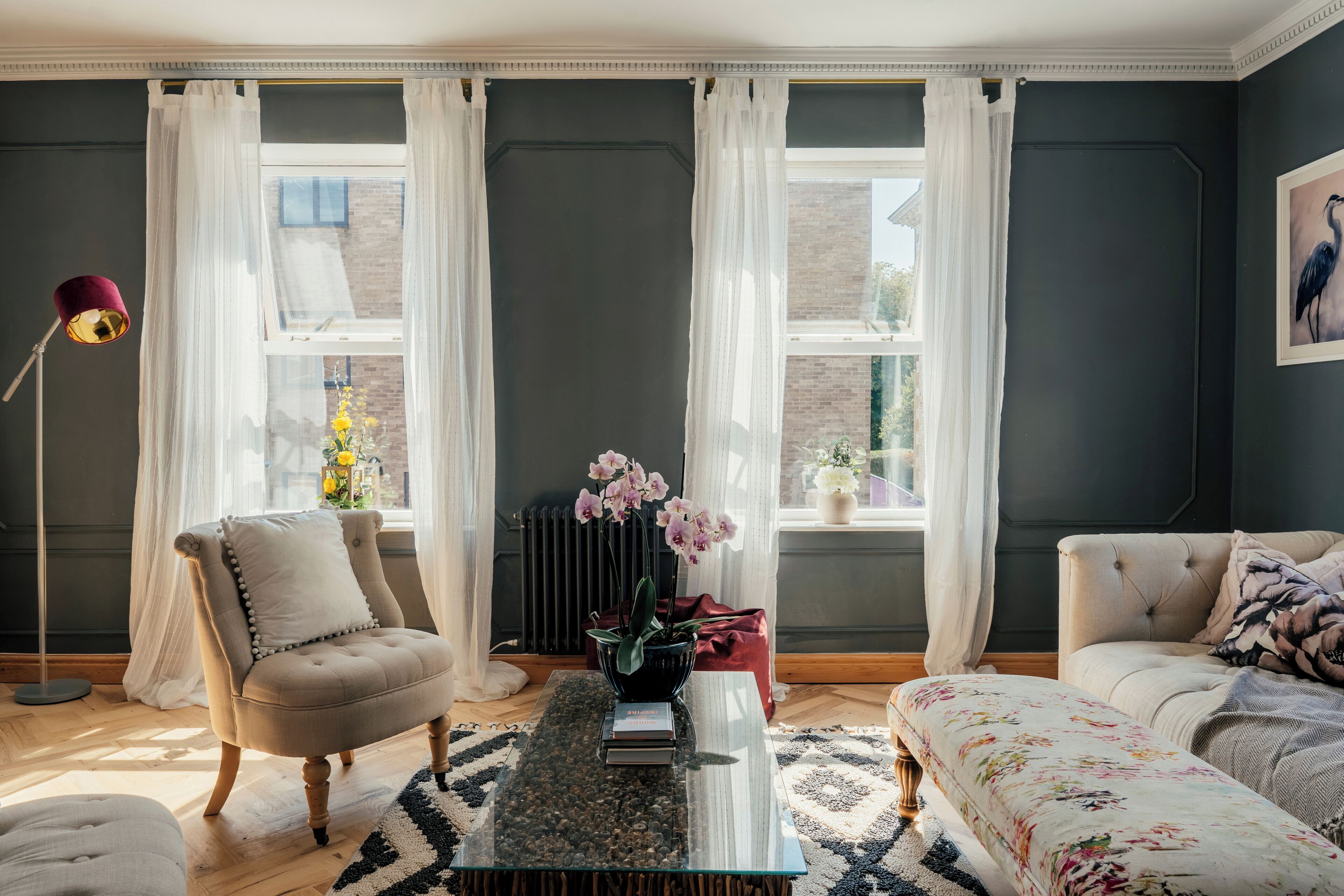 A living room with a sofa, armchair, and a coffee table with books.