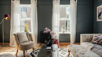 A living room with a sofa, armchair, and a coffee table with books.