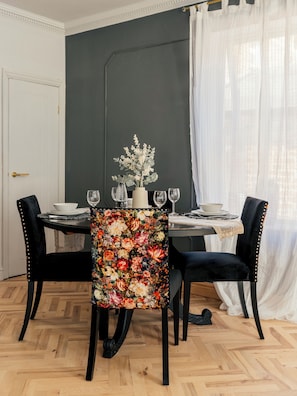 A dining room with a dark wall, a floral tablecloth, and black upholstered chairs. - Gorgeous Central 2BR Apt + Free Parking I Walk to town (Harrogate)