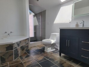 Een moderne badkamer met een bad, toilet en douche.