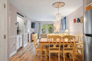 Ein Essbereich mit Holztisch und -stühlen, einer Chandelier und Blick durch ein Fenster.