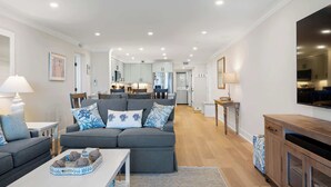 A modern living room with a grey sofa, a coffee table, and a TV mounted on the wall. - Luxury Direct Oceanfront 3BR Panoramic Ocean Views (Hilton Head Island)