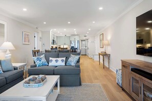 Ein modernes Wohnzimmer mit einem grauen Sofa, einem Couchtisch und einem an der Wand befestigten Fernseher.