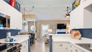 A modern kitchen with white cabinets, a built-in microwave, and a large island with a sink. - Beautiful & Spacious Golf View Villa Next to Pool (Hilton Head)