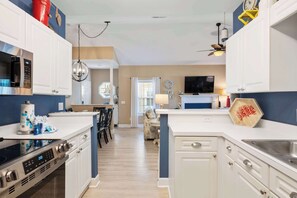 A modern kitchen with white cabinets, a built-in microwave, and a large island with a sink. - Beautiful & Spacious Golf View Villa Next to Pool (Hilton Head)