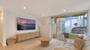 Ein modernes Wohnzimmer mit einem großen Gemälde, einem Sofa, einem Couchtisch und Meerblick durch eine Schiebetür.