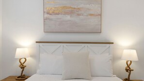 Ein Bett mit Holz-Kopfteil, zwei Nachttischlampen und einem Bild darüber.