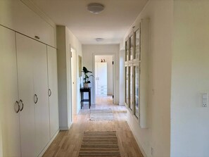 A hallway with wooden flooring, white walls, and a potted plant on a small table. - 4 Star Holiday Home in Vejby (Vejby)
