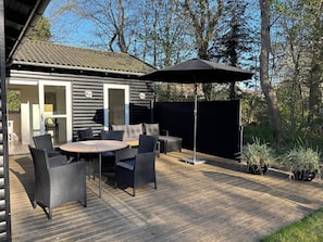A wooden deck with outdoor furniture, a covered patio area, and a view of a cabin with sliding doors. - 4 Star Holiday Home in Vejby (Vejby)