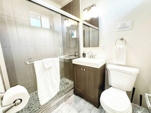 Ein Badezimmer mit Dusche, Toilette, Waschbecken und Spiegel.