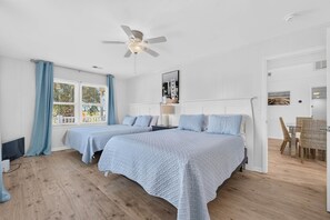 A hotel room with two beds, a ceiling fan, a dining area with wicker chairs, and a view of the outdoors through the window. - Private Dock and walk to beach. 4-bedroom house in beautiful OIB (Ocean Isle Beach)