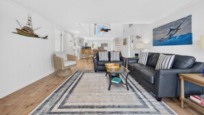 Ein geräumiger Wohnbereich mit einer Couch, einem Couchtisch und einem Essbereich im Hintergrund.