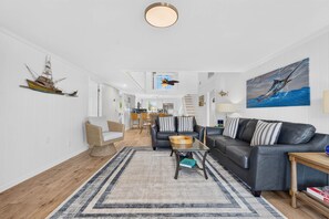 A spacious living area with a sofa, coffee table, and a dining area in the background. - Private Dock and walk to beach. 4-bedroom house in beautiful OIB (Ocean Isle Beach)