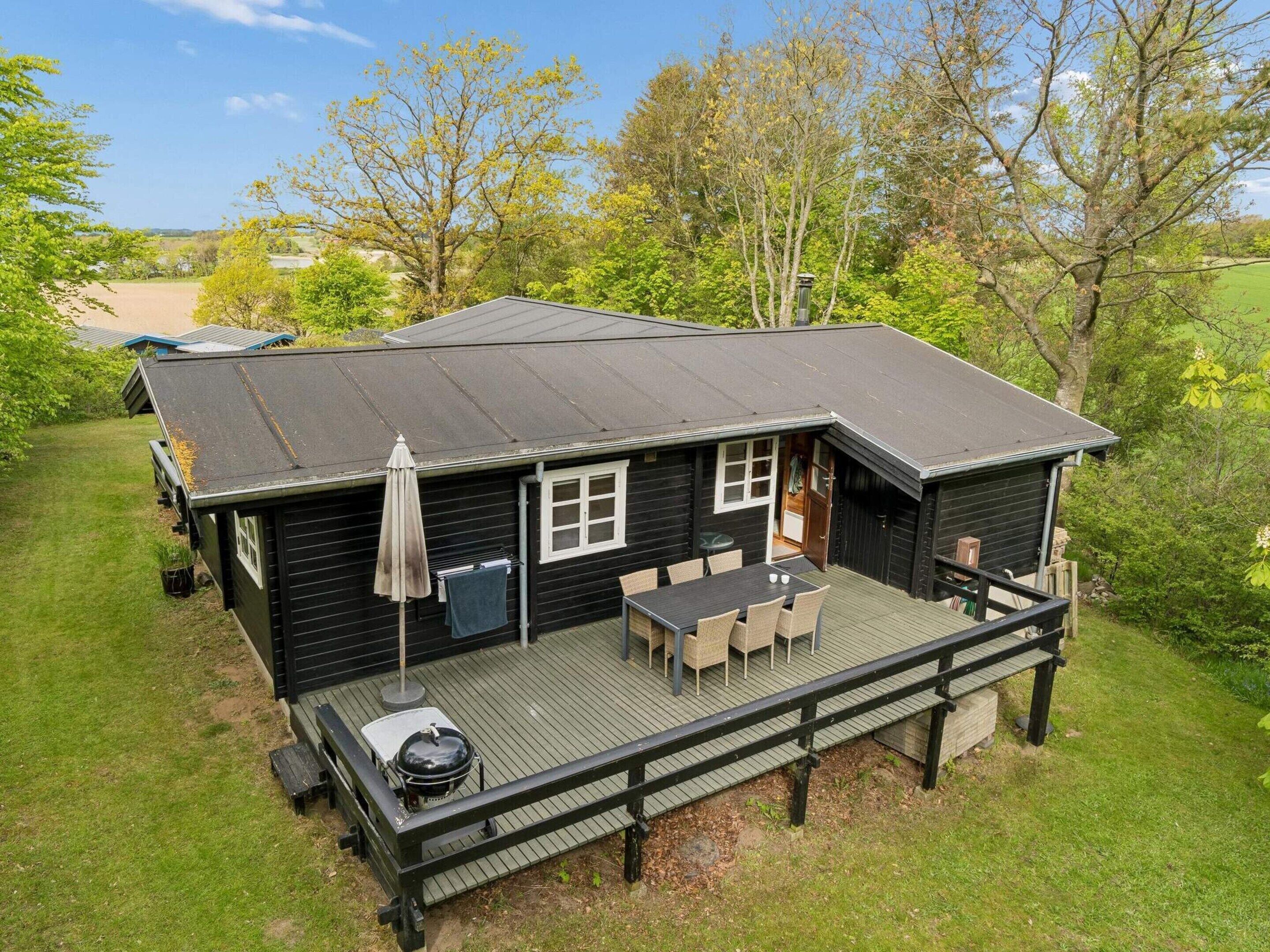 A cabin with a deck, outdoor seating, and a grill.