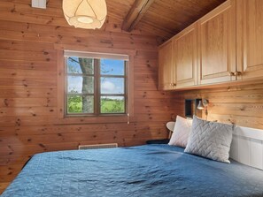 A wooden cabin bedroom with a bed, a window, and a ceiling light. - 4 Star Holiday Home in Roslev (Roslev)