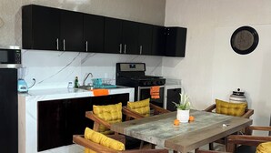 A kitchen with black cabinets, a microwave, a stove, and a dining table with wooden chairs. - Casa Tonala 3 Rec. Wifi.A/c. FIFA 2026/GDL AirPort (Tonalá)