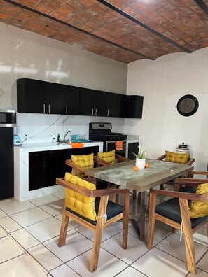 A kitchen with black cabinets, a microwave, a stove, and a dining table with wooden chairs.