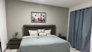 A neatly arranged bedroom with a bed, a bedside table with a plant, a framed artwork on the wall, and a welcome mat on the floor. - Casa Tonala 3 Rec. Wifi.A/c. FIFA 2026/GDL AirPort (Tonalá)