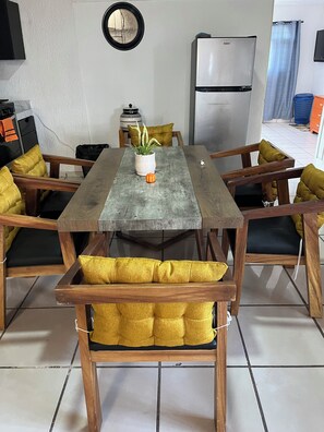 A dining area with a wooden table, chairs with yellow cushions, a potted plant, and a refrigerator in the background. - Casa Tonala 3 Rec. Wifi.A/c. FIFA 2026/GDL AirPort (Tonalá)