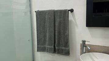 A bathroom with a toilet, a sink, a towel rack, and a glass shower enclosure.