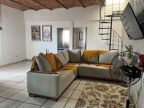 A living room with a sectional sofa, a standing fan, and a patterned rug. - Casa Tonala 3 Rec. Wifi.A/c. FIFA 2026/GDL AirPort (Tonalá)