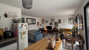 Een moderne keuken met een houten kookeiland, een eethoek met een tafel en stoelen, een blauwe bank en een groot raam.
