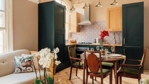 A modern kitchen with dark cabinets, a dining area with wooden chairs, and a sofa with decorative pillows. - Spacious Central Duplex, Walk to town + 2x Parking (Harrogate)