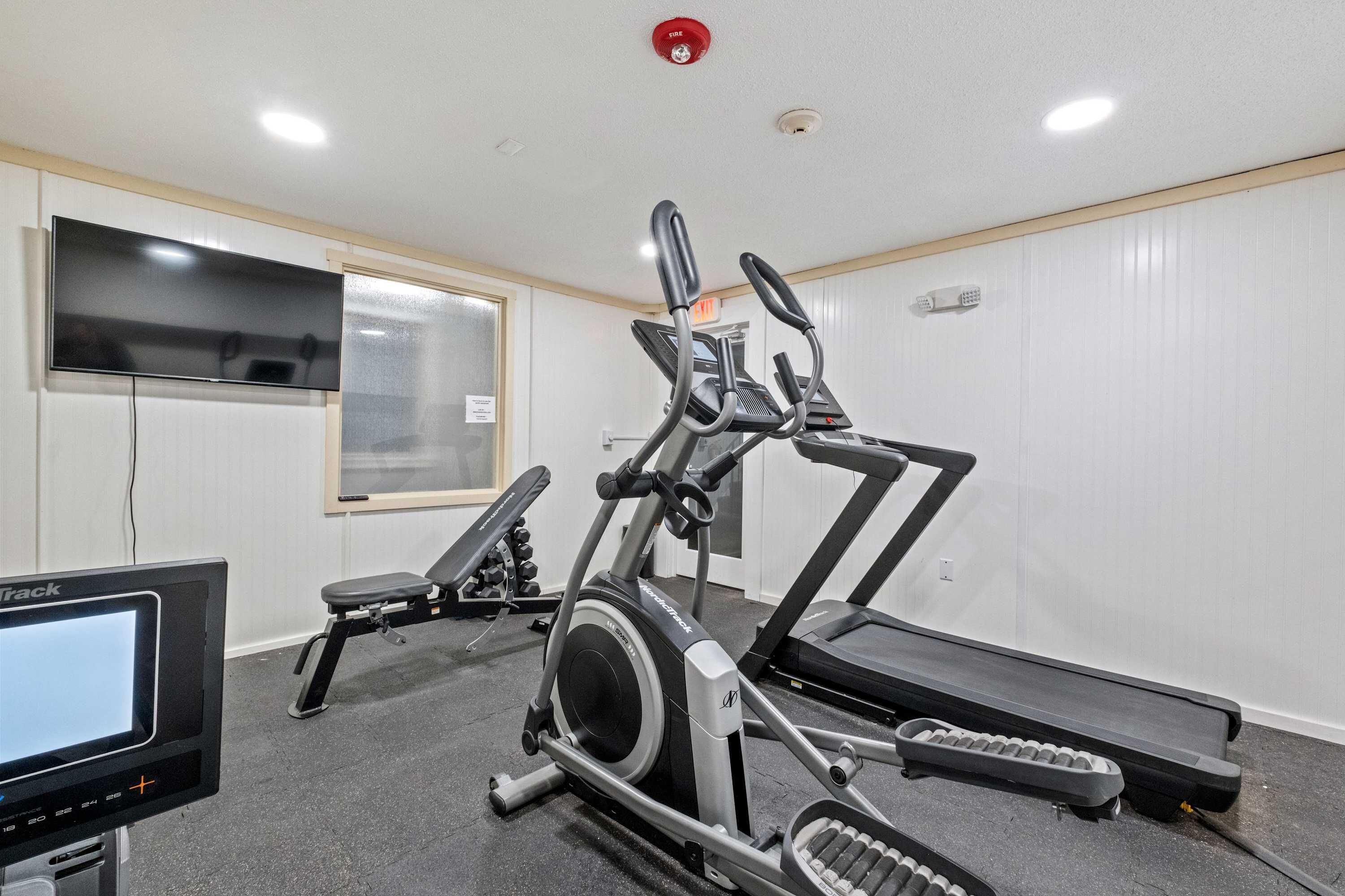 A gym with treadmills, an elliptical, and a stationary bike.