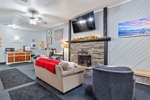 Ein Wohnzimmer mit Kamin, einer Couch, einem Fernseher und einer Küche im Hintergrund.