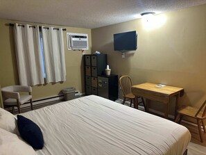 Ein Hotelzimmer mit Bett, Schreibtisch, Stuhl, Fernseher und Stauraum.