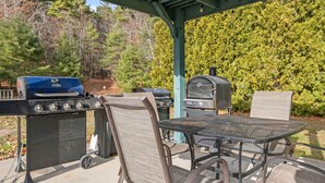 Une terrasse extérieure avec un barbecue, une table et des chaises.