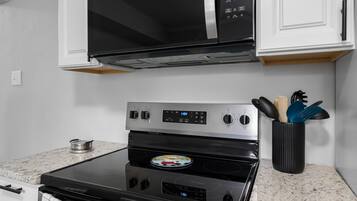 A kitchen with a microwave, oven, and a spice rack.