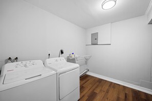 Ein Waschraum mit zwei weißen Waschmaschinen, einem Ablagefach für Toilettenartikel und einem kleinen Schrank.
