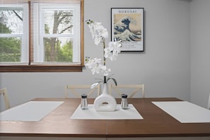 A dining table with a white vase and orchid, two salt shakers, and a framed artwork on the wall. - Charming 3-bedroom house in beautiful St. Louis. (St. Louis)
