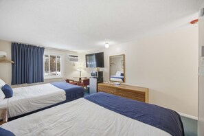 A hotel room with two beds, a desk, a mirror, a dresser, and a window with curtains. - Eastern Inn Ridge Retreat Suite (North Conway)