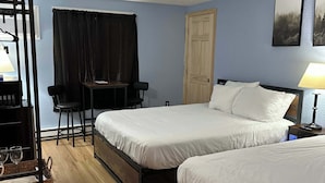A hotel room with two beds, a desk, a chair, a lamp, and a door. - Eastern Inn Ridge Retreat Suite (North Conway)
