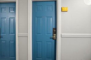 Zwei blaue Türen mit Messinggriffen, ein gelbes Schild mit der Nummer '107' und eine weiße Wand.