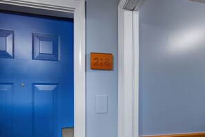 A blue door with a number plate indicating room 216, a light switch, and a white wall. - Eastern Inn Scenic Retreat NH (North Conway)