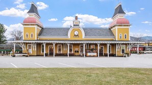 Un edificio amarillo con dos cúpulas rojas y un reloj, probablemente una estación de tren.