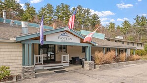 Un edificio con un letrero que dice 'Eastern Inn & Suites', un asta con la bandera estadounidense y una bandera con un diseño de montaña.