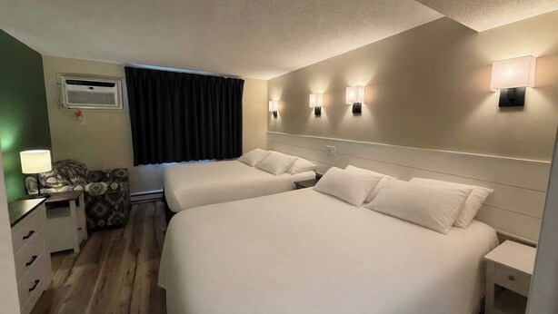 Habitación de hotel con dos camas, un escritorio, una silla y una ventana con cortinas.