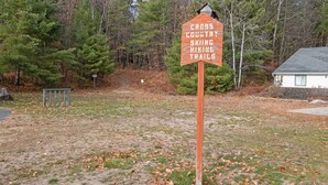 Un panneau indiquant les « sentiers de ski de fond et de randonnée », entouré d’arbres et d’un bâtiment.
