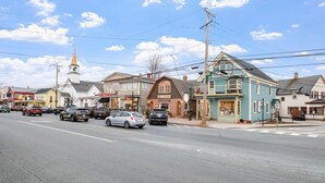 Une vue de rue avec des immeubles, des voitures et le clocher d’une église.